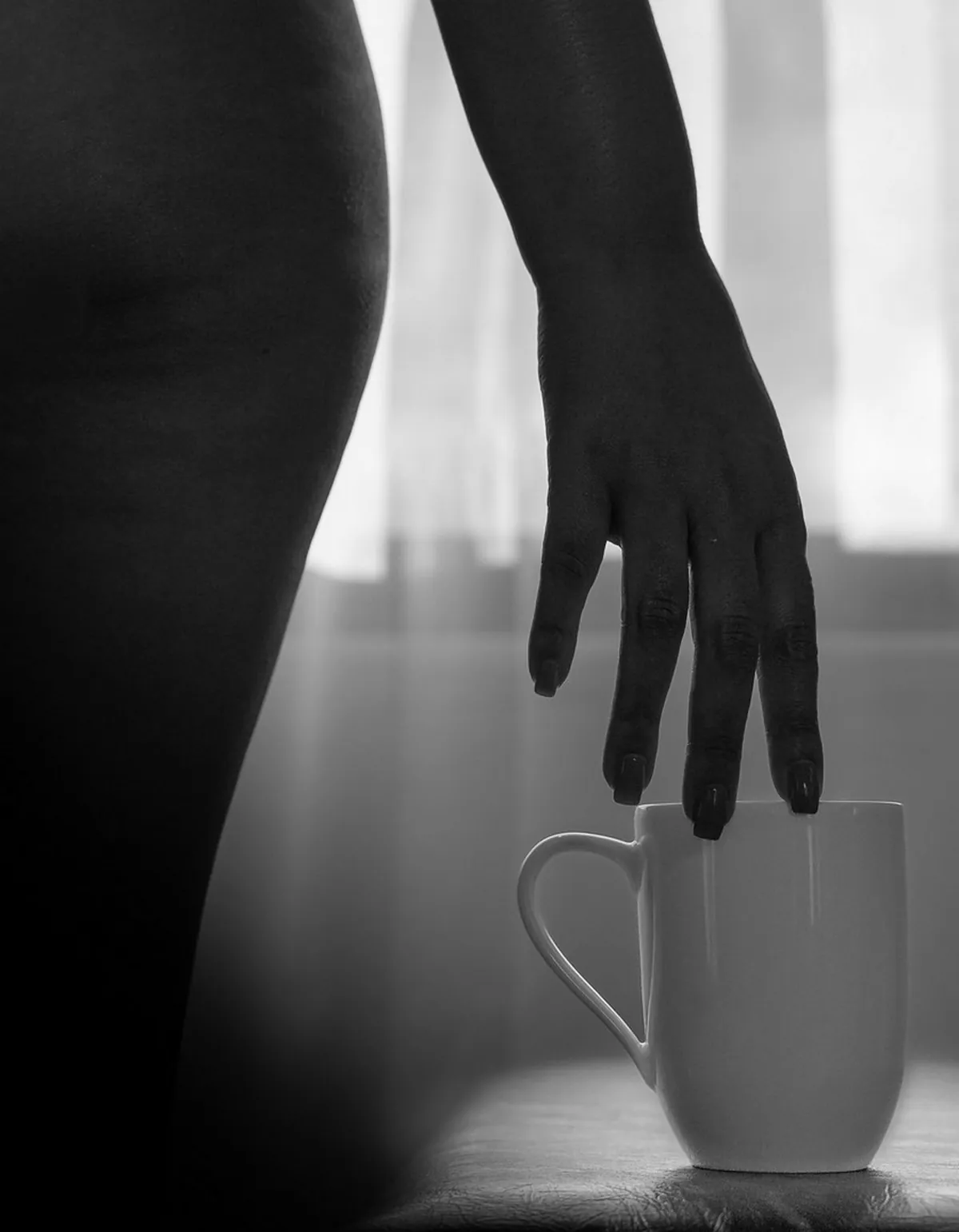 Artistic black-and-white detail of a woman's hand against soft window light