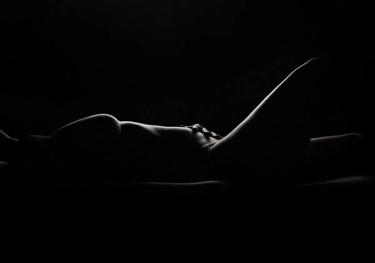 Long-exposure light drawing tracing the outline of a reclining female form