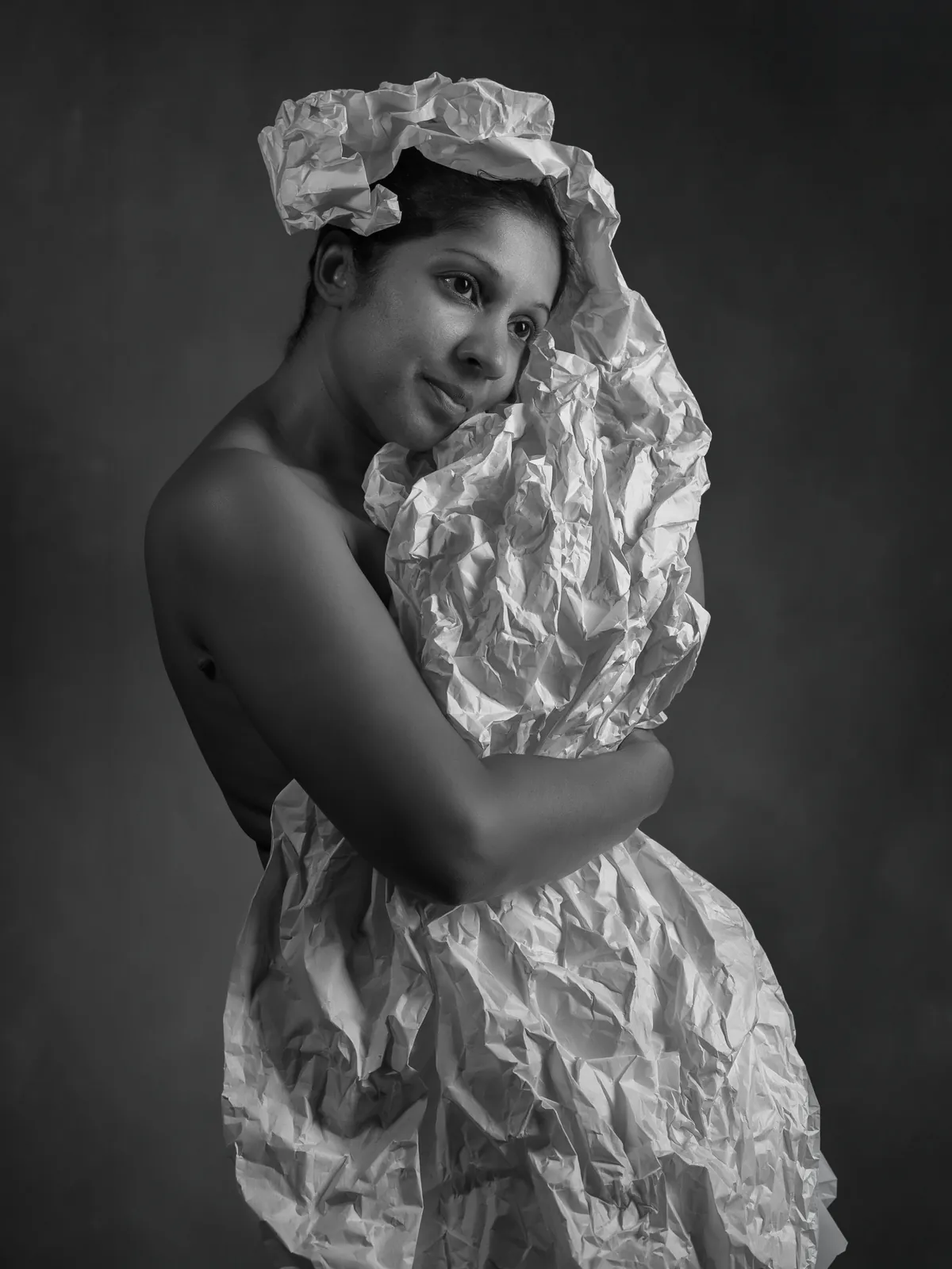 Black-and-white fine-art portrait of a woman partly wrapped in sculptural white fabric