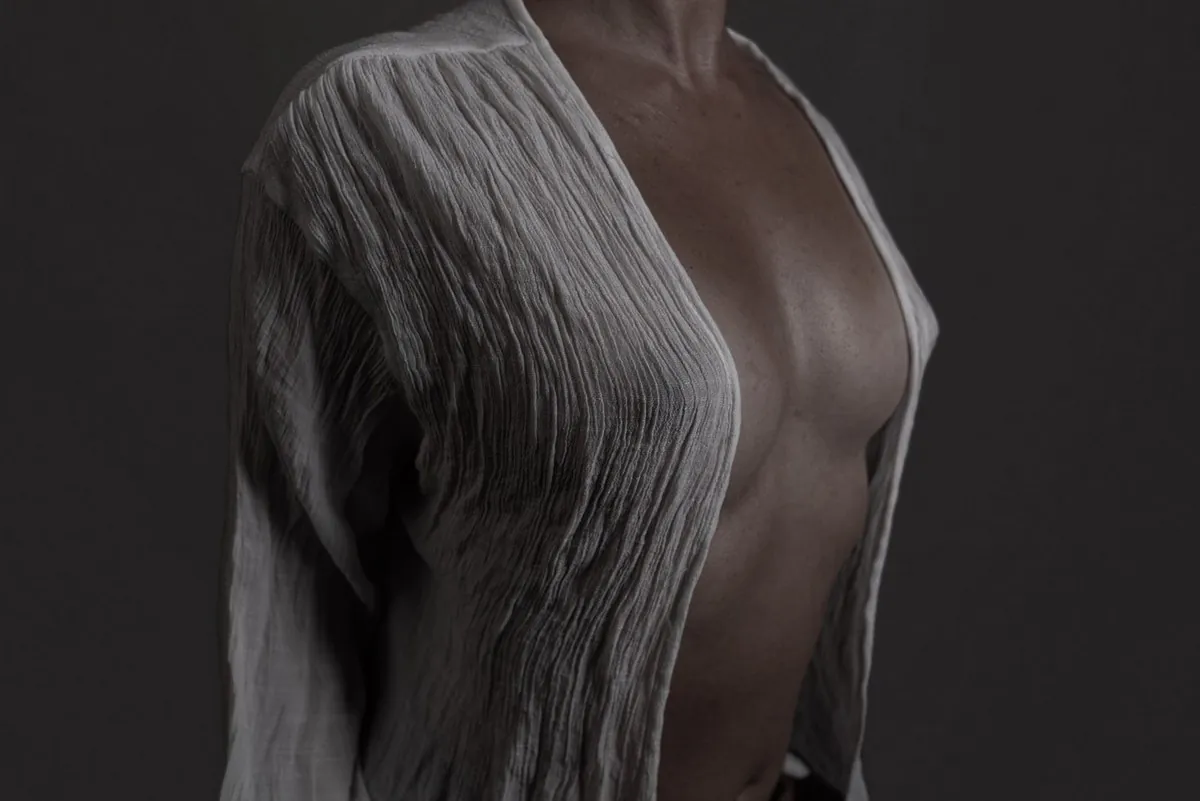 Close-up semi-nude detail of a woman wearing a textured white knit top