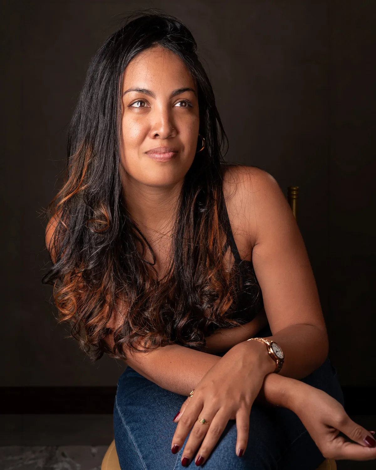 Casual seated photograph of Emilie against a dark studio background