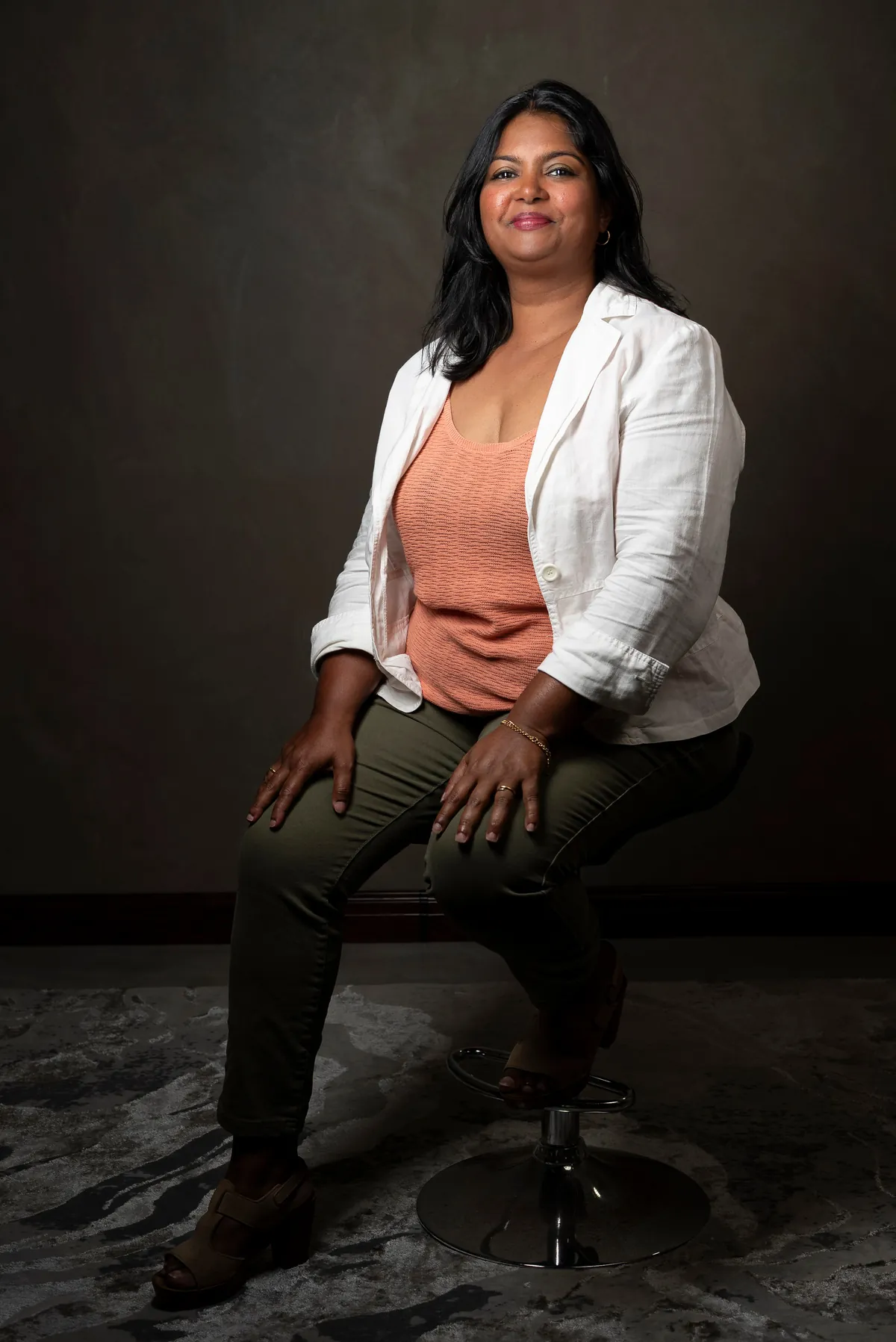Full-body professional portrait of Caroline Louise seated in a photography studio