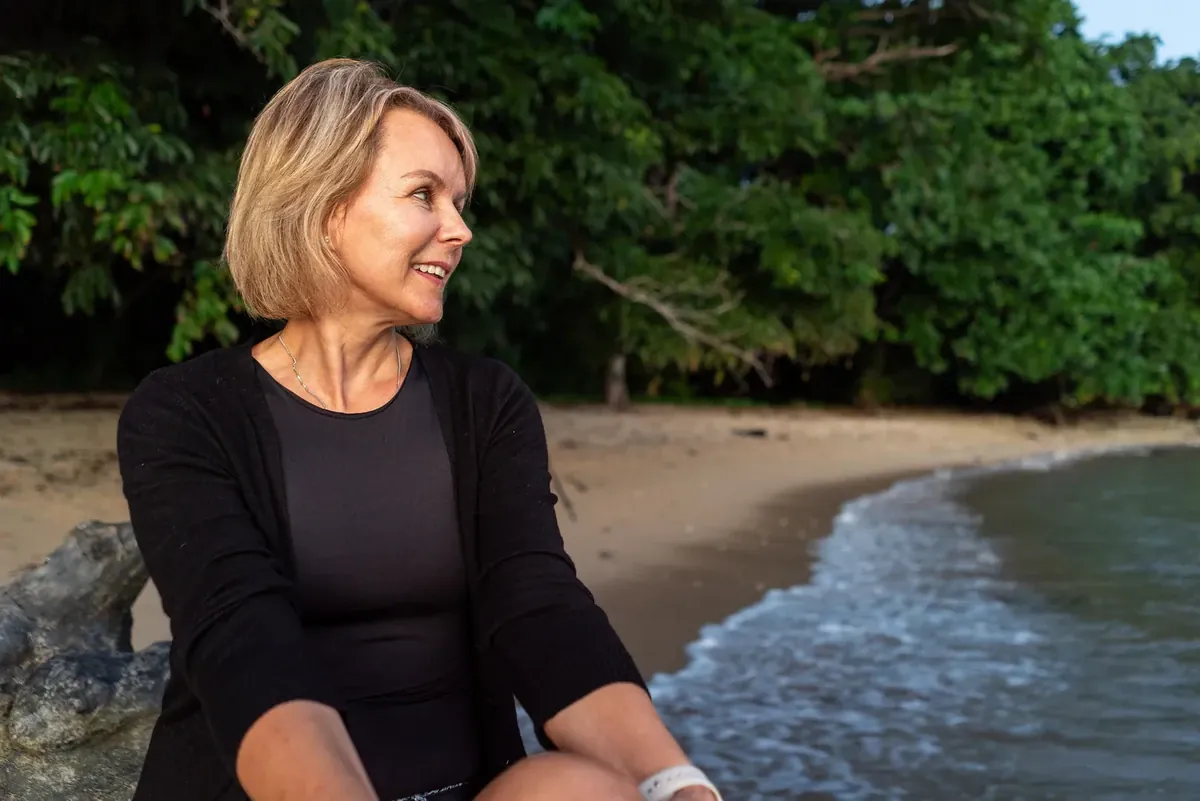 Relaxed casual portrait of Deborah seated beside the beach