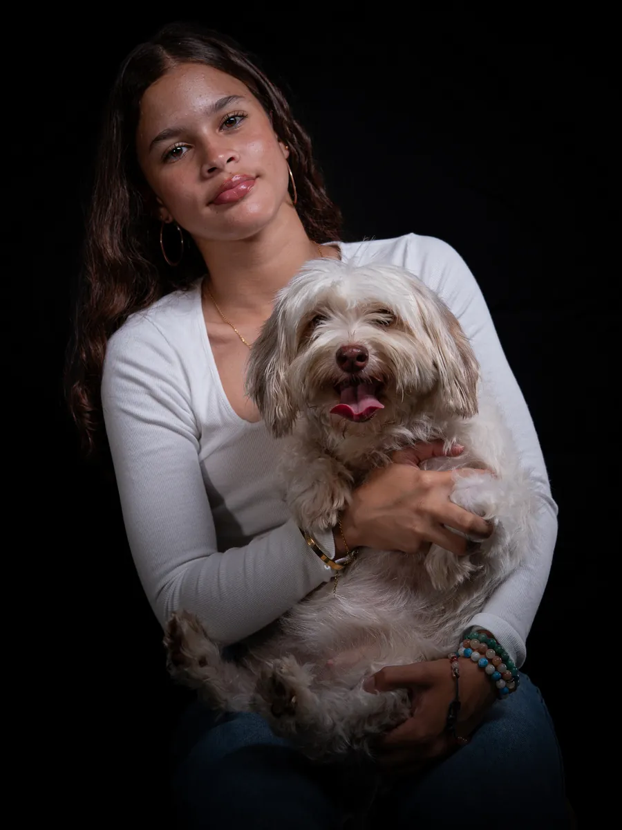 Teenage girl holding her dog during a relaxed pet photography session in the studio