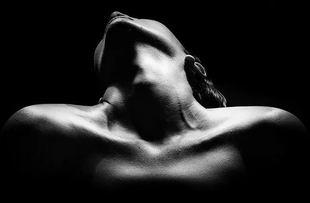 Abstract portrait of nude woman in studio looking upward under artistic lighting