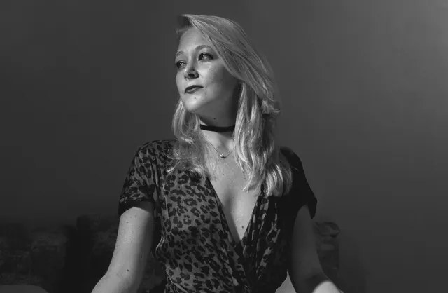 Brown dress portrait of girl doing wide leg yoga pose on white sheet bed