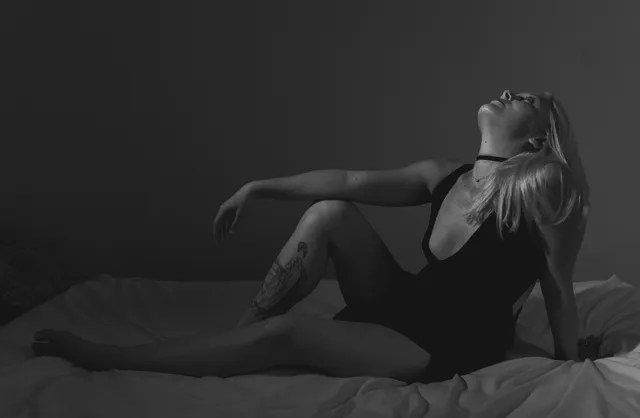 Black and white image of woman in dress reclining for boudoir photography service