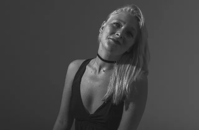 Minimal lingerie photography of woman in white crochet sweater kneeling on bed