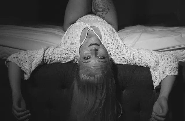 Girl with legs raised and head upside down during sensual studio photoshoot