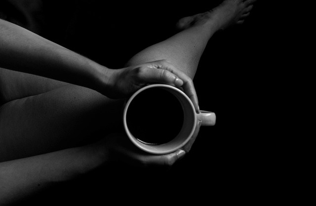 Young woman enjoying tea in bed during casual boudoir photography session