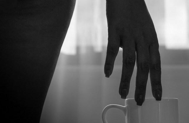 Black and white boudoir photo of a woman’s hand grazing a coffee mug