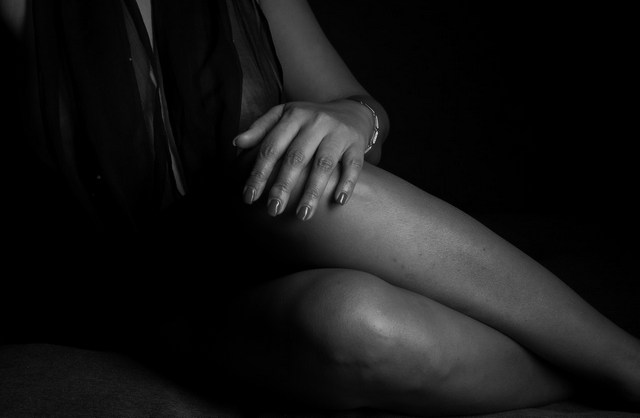 Elegant boudoir photo in neutral color of a woman’s hand resting gently on her knee in Mauritius