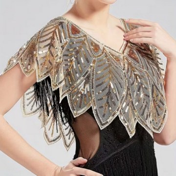 Woman wearing a gold and silver sequin shoulder cape over a black dress during a studio photoshoot.